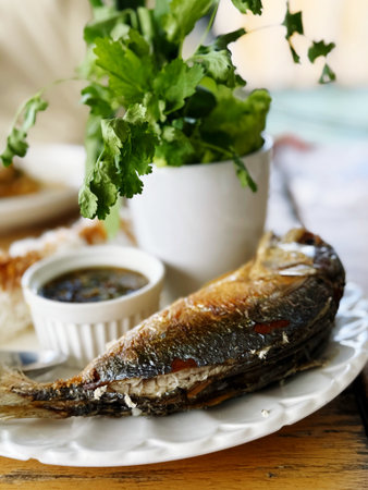 Fried fish with sauce and parsley on a wooden table.の写真素材