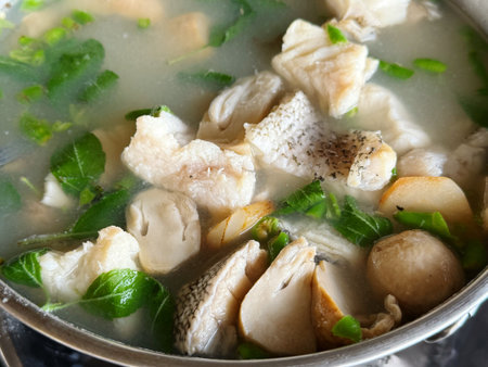Chicken soup with mushrooms and herbs in a metal bowl on a dark backgroundの写真素材