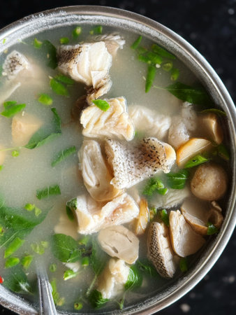 Fish soup with mushrooms and parsley, top view, close-up