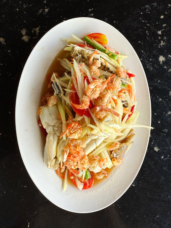 Thai spicy papaya salad with shrimp and crab on black background