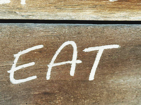 eat written in white chalk on an old wooden bench, close upの写真素材