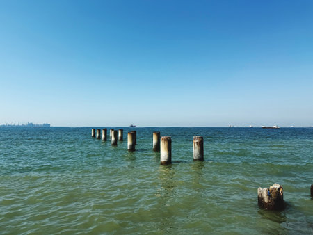 Wooden breakwaters in the sea on a background of blue skyの写真素材