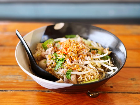 Thai noodle with pork and vegetables in bowl on wooden table