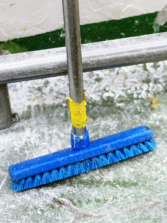 close up of a broom cleaning the floor with a blue handle.の写真素材