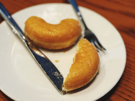 Heart-shaped donut on a white plate with fork and knife