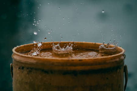 Rain water drop falling to the pail in heavy rain dayの写真素材