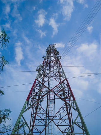Photography of a High voltage tower, power line with electric cables and insulators against a blue sky with clouds and copy space.の写真素材