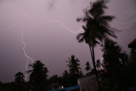 Thunder, lightning storm in the raining night background over a house and palm tree. In Mumbaiの写真素材