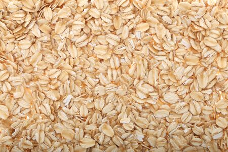 Oat flakes, uncooked oats in bowl with poon and wheat ears on white background. Concept of healthy eating, vegan food, healthy food, breakfast.の写真素材