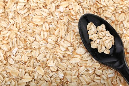 Oat flakes, uncooked oats in bowl with poon and wheat ears on white background. Concept of healthy eating, vegan food, healthy food, breakfast.の写真素材