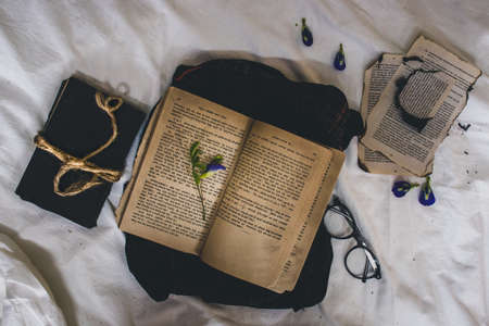 Open book, glasses, a hat and a bouquet of flowers lie on the bedの写真素材