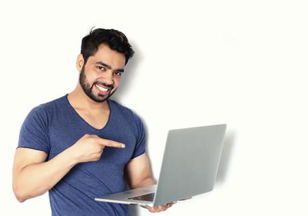 A handsome young Indian man working on laptop against a white backgroundの写真素材