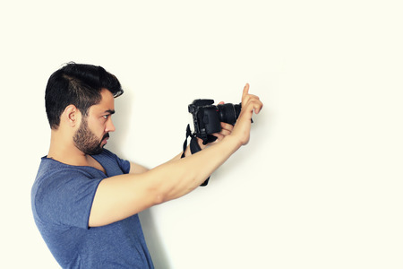 Young indian Photographer holding a dslr photo camera isolated on white backgroundの写真素材