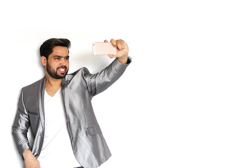 Young Indian Businessman photographing of himself against the white backgroundの写真素材