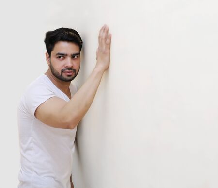 Portrait of thoughtful young handsome Indian man against the white Wallの写真素材