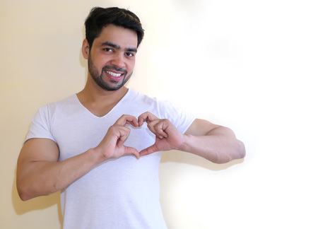 Young Indian man doing a heart gesture - isolated white backgroundの写真素材