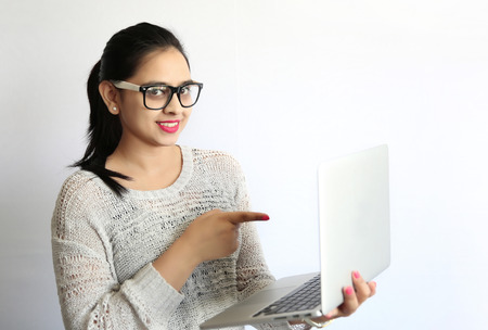 Beautiful indian woman pointing at laptop screen against white background.の写真素材