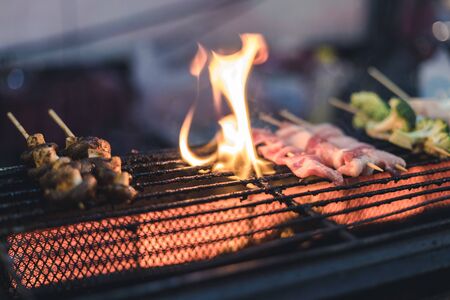 pork and some vegetable are grilling on stove that look like use so many time and got some fire on topの写真素材