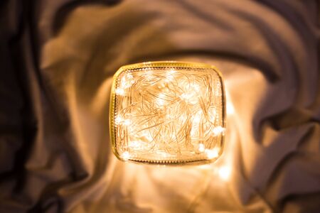 top view of LED light bulb wire full in glass cup upside down set on white clothの写真素材