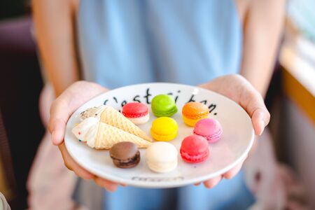 Mix color of macaroon on wihte plate with french language holding on girl hand in blueの写真素材