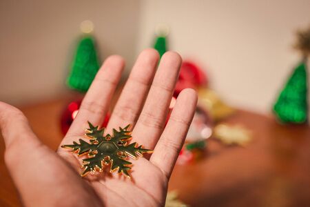 close up snow flake on bare hand is putting with others christmas decorの写真素材