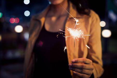 lady hold firesparkler blink in her hand at night toning