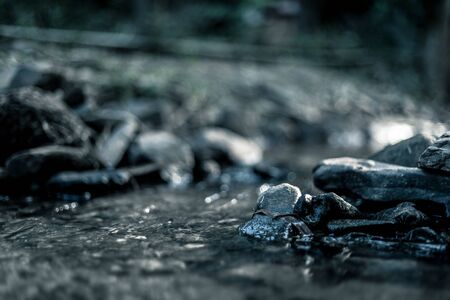 close up of stone that use to make weir in river with water steam flowing, made in dramatic toneの写真素材