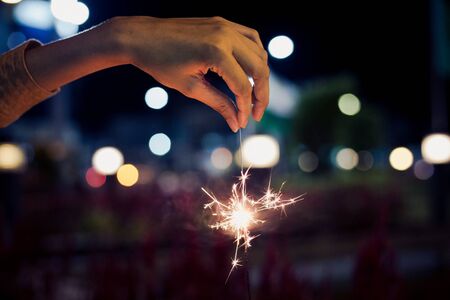 hold firesparkler blink in hand upside down at night toningの写真素材
