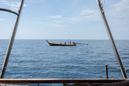 sea view with long tail boat in center looking out from inside big boat. have some Thai word on the boatのeditorial素材