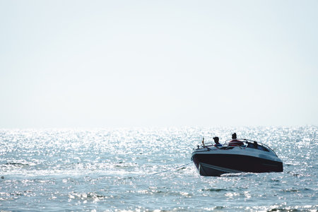Silhouette mini speed boat for hook parachute playing on the sea water with sun shine on make bokeh...