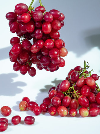 Vibrant red grapes arranged in clusters against a clean white background. Perfect for showcasing healthy snacks or natural food concepts.の写真素材