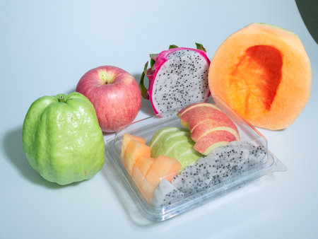A vibrant arrangement of fresh fruits including apple, guava, melon, and dragonfruit in packaging. Perfect for healthy snacks and colorful presentations.の写真素材