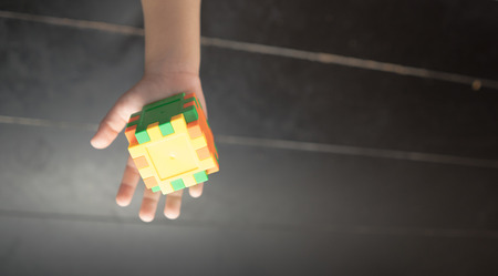 Child's hand holding colorful toy cubeの写真素材