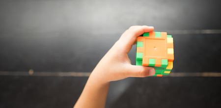 Child's hand holding colorful toy cubeの写真素材