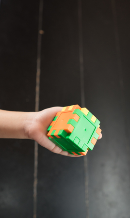 Child's hand holding colorful toy cubeの写真素材
