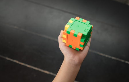 Child's hand holding colorful toy cubeの写真素材