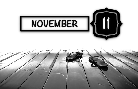 Flip-flop on wooden deck with NOVEMBER word-Calendar Conceptの写真素材