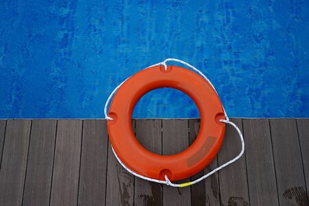 Orange life buoy on wooden deck near swimming poolの写真素材