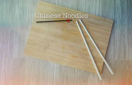 Chopsticks and chopping board on wooden table with word CHINESE NOODLESの写真素材