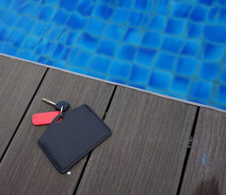 Square Plastic Tag with Copy Space and Key on Wooden Deck near Swimming Poolの写真素材