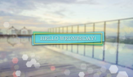 Word HELLO WEDNESDAY on blurred background of sunrise over an infinity swimming poolの写真素材