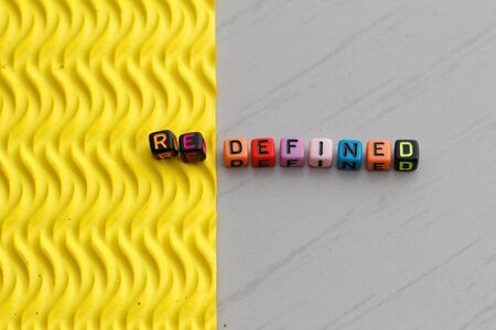 Plastic alphabet block arranged to form word REDEFINED. Two different texture represent the word...