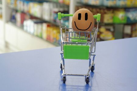 Egg happily smiling inside a mini trolley with blurred background of shop interior. Conceptualの写真素材