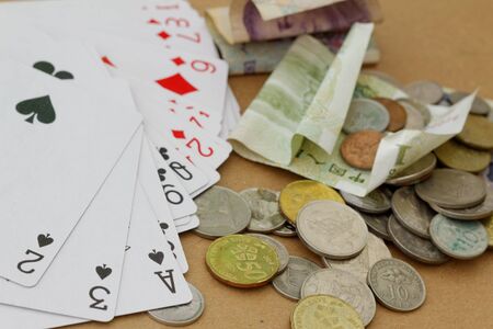Playing cards and money in different currency. Concept of gambling, addiction, online.