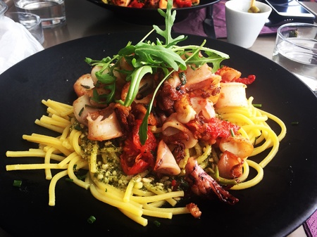 A seafood pasta in pesto sauce served in a black plateの素材