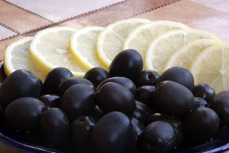 black olive with lemon segments on plateの写真素材