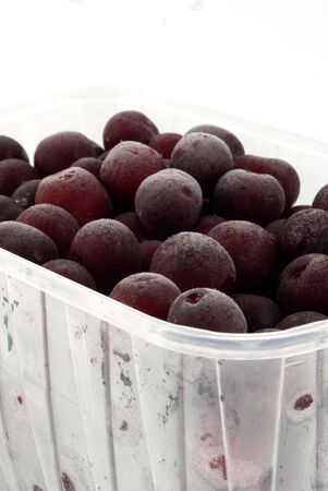 quick-frozen cherrys in plastic container against white backgroundの写真素材