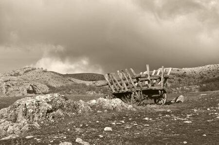 deserted cart on grass against mountain  black and whiteの写真素材