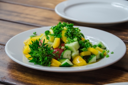 raw vegetables with greens on plate on tableの写真素材