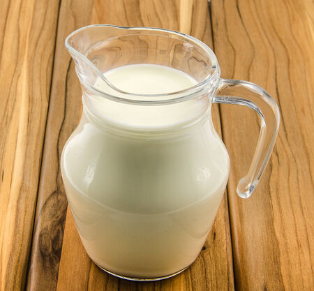 milk in glass jag on plank tableの写真素材